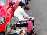La mujer ayuda y sus dos hijos estudiando en la calle.