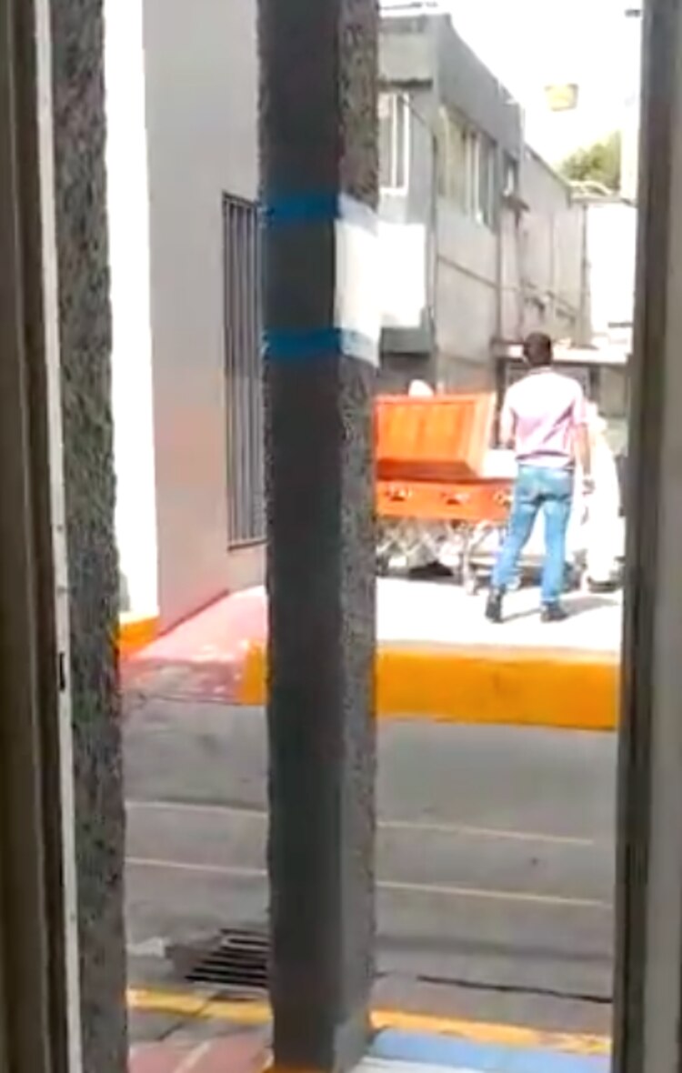 Familiares y trabajadores vestidos de civil presencian las labores para colocar cuerpos en ataúdes.