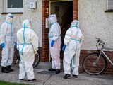 Miembros de la Cruz Roja Alemana, de pie ante una casa donde viven empleados de la planta cárnica de Toennies, en Rheda-Wiedenbrueck, Alemania, el lunes 22 de junio de 2020.