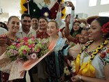Grupo de mujeres con trajes tehuana dan la bienvenida a Claudia Sheinbaum con un colorido arreglo floral en Oaxaca.