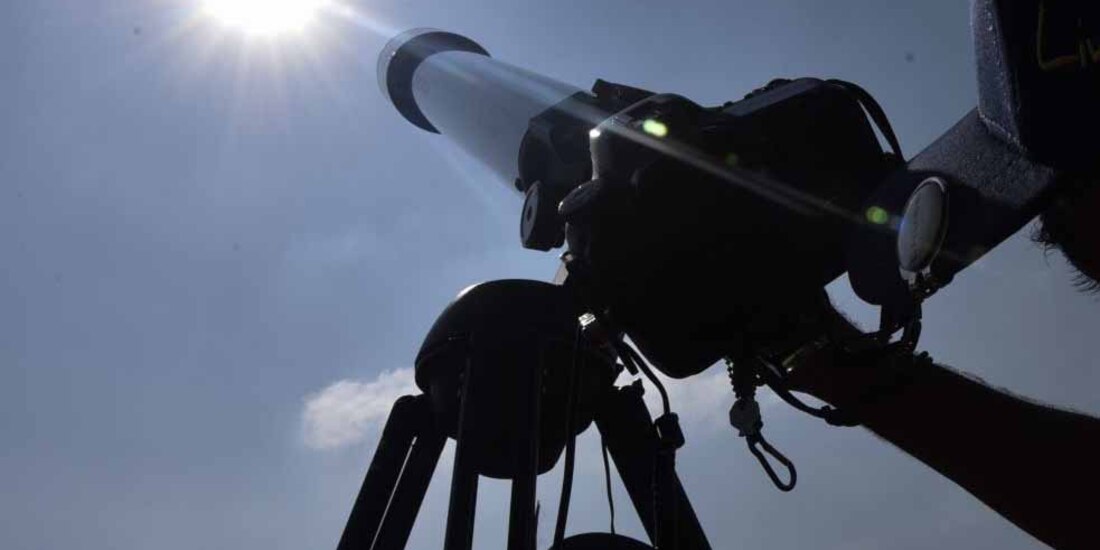 Estudiantes observan el sol con telescopios.