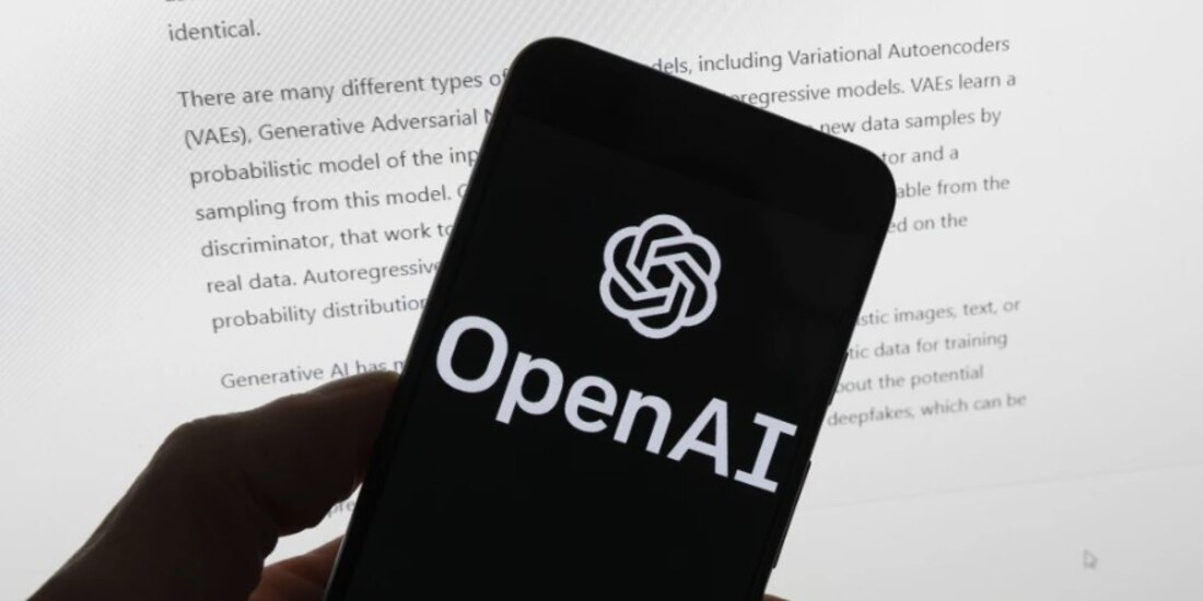 El logotipo de OpenAI se ve en un teléfono móvil frente a una pantalla de computadora que muestra el resultado de ChatGPT.