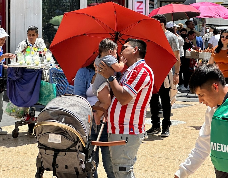 Un padre de familia sostiene a su bebé en calles de la Ciudad de México, el domingo 21 de junio de 2026.