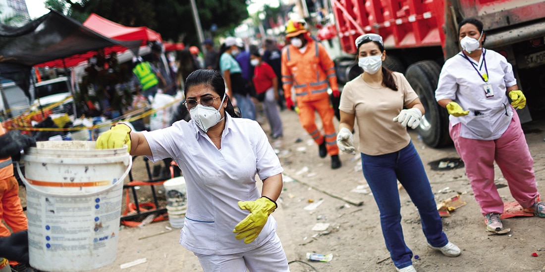 Una enfermera que trabaja en un hospital frente a un edificio derrumbado, ayuda a limpiar los escombros, ayer.