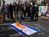 Manifestantes iraníes queman una bandera de Israel.