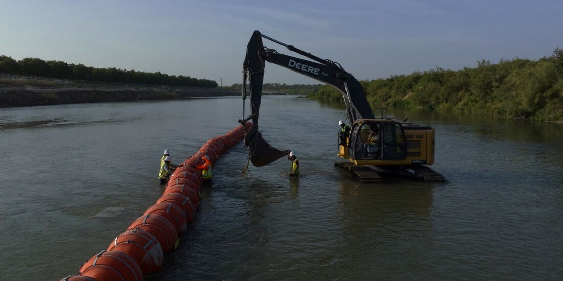 Trabajadores montan una cadena de grandes boyas, para disuadir a los migrantes que cruzan a través del río Grande, en la frontera internacional con México en Eagle Pass, Texas.