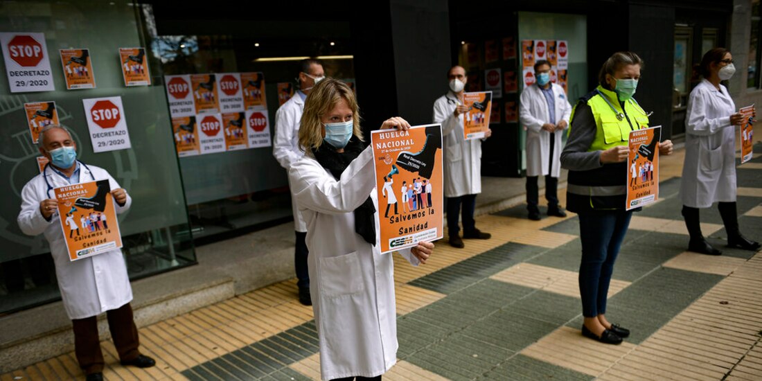Una trabajadora de la salud alza un cartel por la huelga general para exigir mayor protección en su trabajo, Pamplona, España.