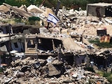 Una bandera israelí ondea en un edificio destruido en el sur del Líbano, vista desde el norte del país, ayer.