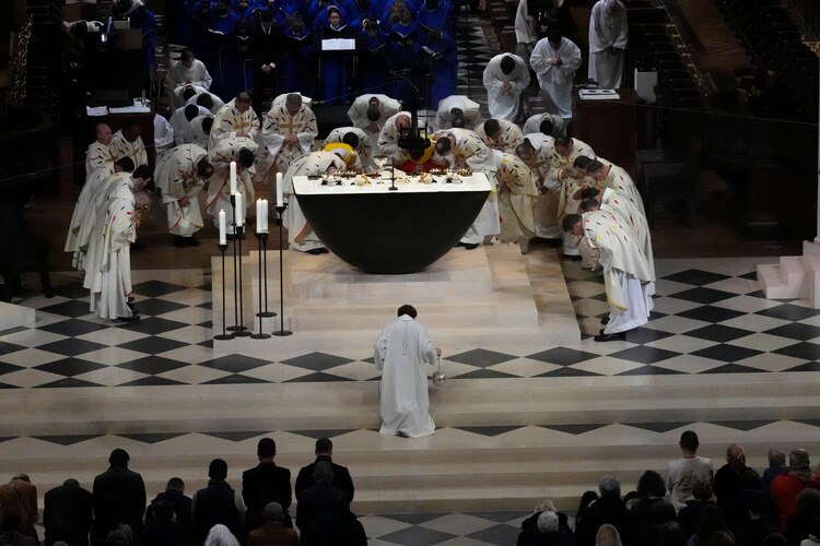 Cllérigos se inclinan en el altar en la primera misa.