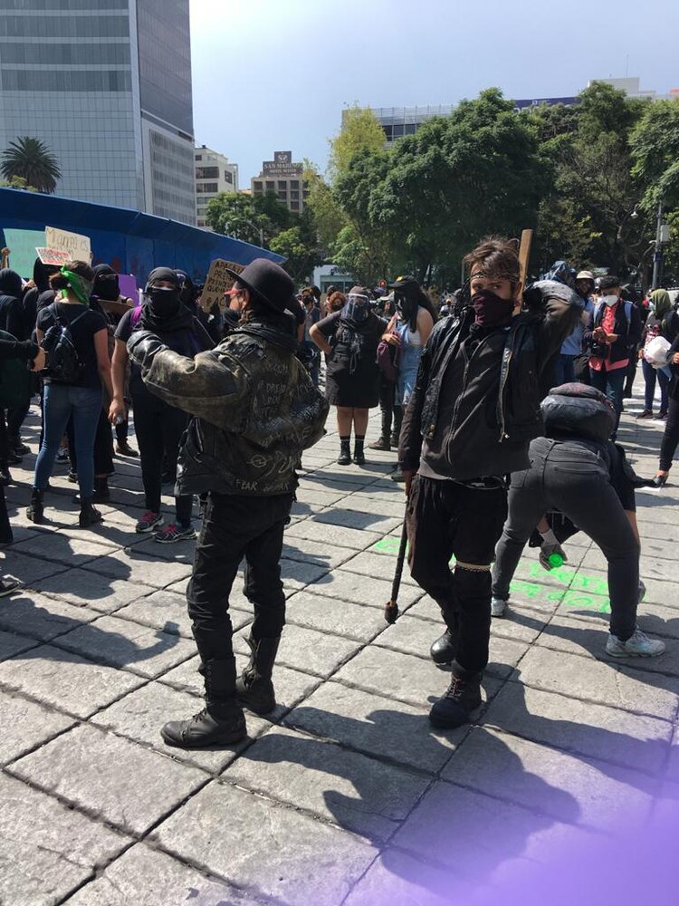Sujetos con palos y vestidos de negro se suman a la marcha en el Ángel de la Indepencia.