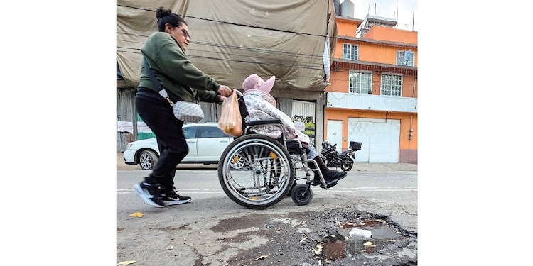 UNA MUJER en silla de ruedas es empujada por otra en la CDMX, en foto de archivo.