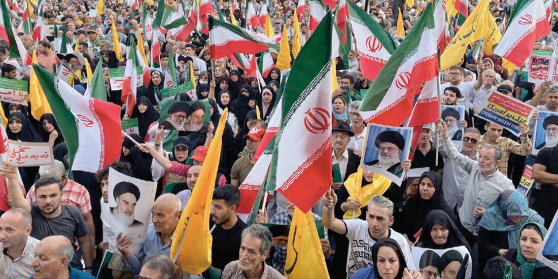 Manifestantes portan banderas y carteles nacionales iraníes mientras corean consignas contra EU e Israel, en Teherán, ayer.