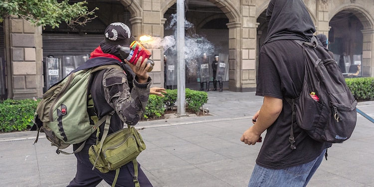 Jóvenes lanzan una bomba incendiaria hacia los edificios públicos.