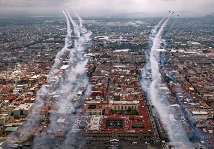 Aviones de la Fuerza Aérea sobrevuelan las calles de la capital, lanzando humo de colores, ayer.