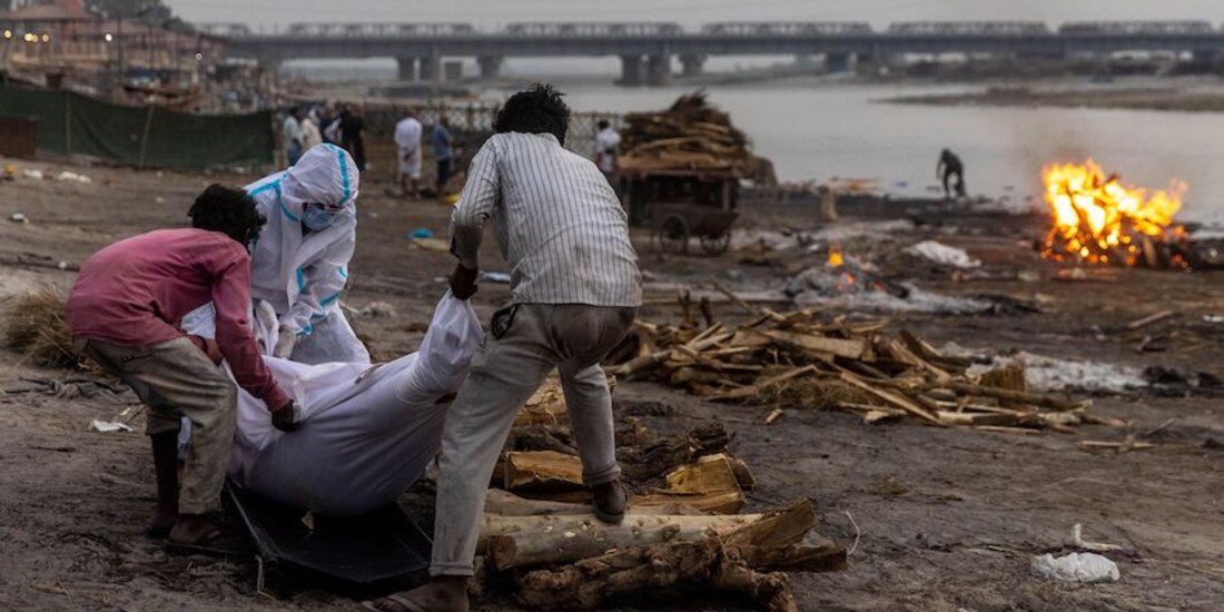Tres hombres colocan un cuerpo en una pira funeraria a orillas del río Ganges en Uttar Pradesh, la semana pasada.