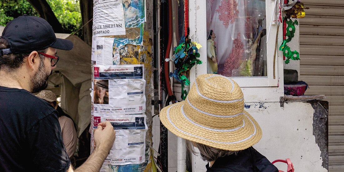 UN PAR de personas coloca en un poste el boletín de búsqueda de Jenny Bolívar, ayer.