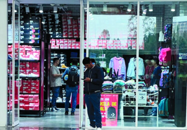 Tres empleados en una tienda de tenis junto a un cliente.