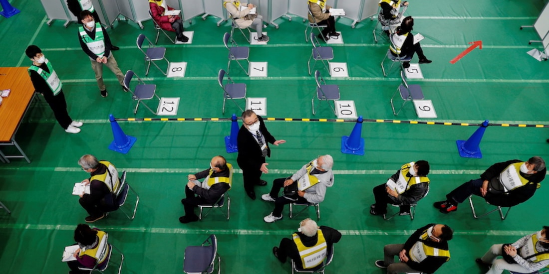 Participantes de un simulacro de vacunación contra Covid-19 esperan su turno en un gimnasio universitario de la ciudad japonesa de Kawasaki, ayer.