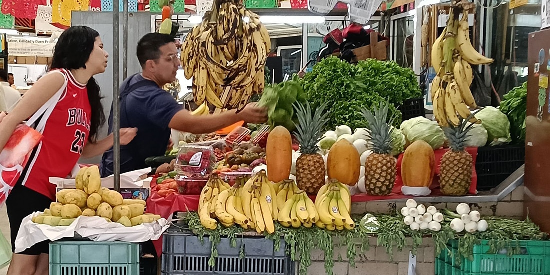 Dos personas compran alimentos en un local de frutas