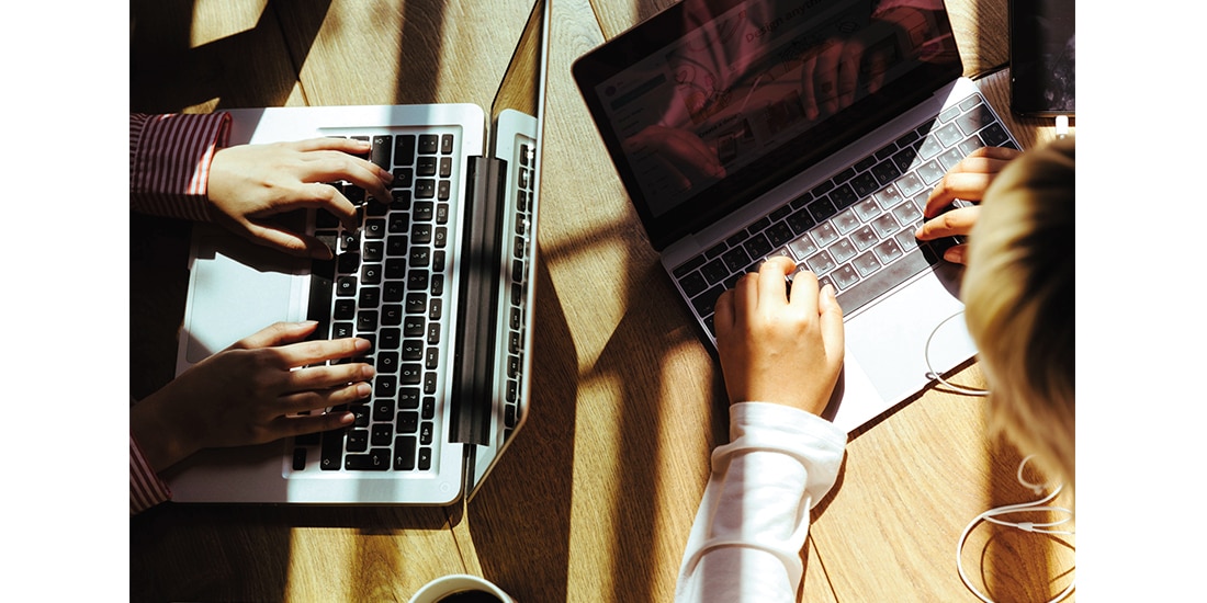 Personas trabajan bajo los rayos del sol en sus computadoras.