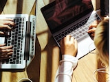 Personas trabajan bajo los rayos del sol en sus computadoras.