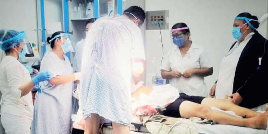 Aún en bata de hospital el ortopedista ayuda a compañeros médicos para detener una hemorragia.