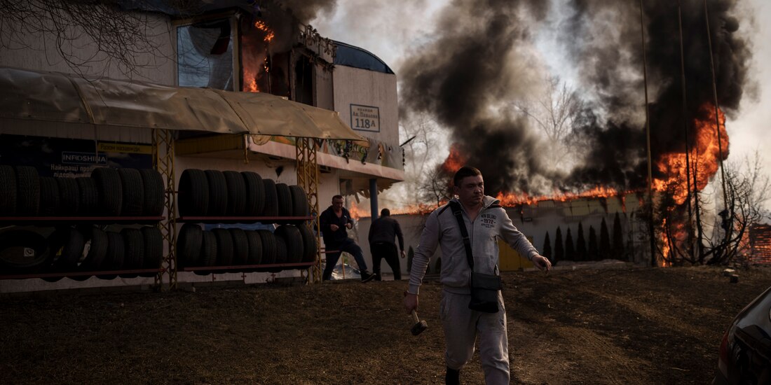 Personas intentan recuperar artículos de una tienda en llamas tras un ataque ruso