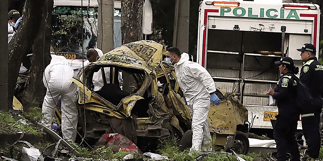Forenses inspeccionan el lugar de la explosión de una bomba a las afueras de una base de la fuerza Aérea en Cali, ayer.