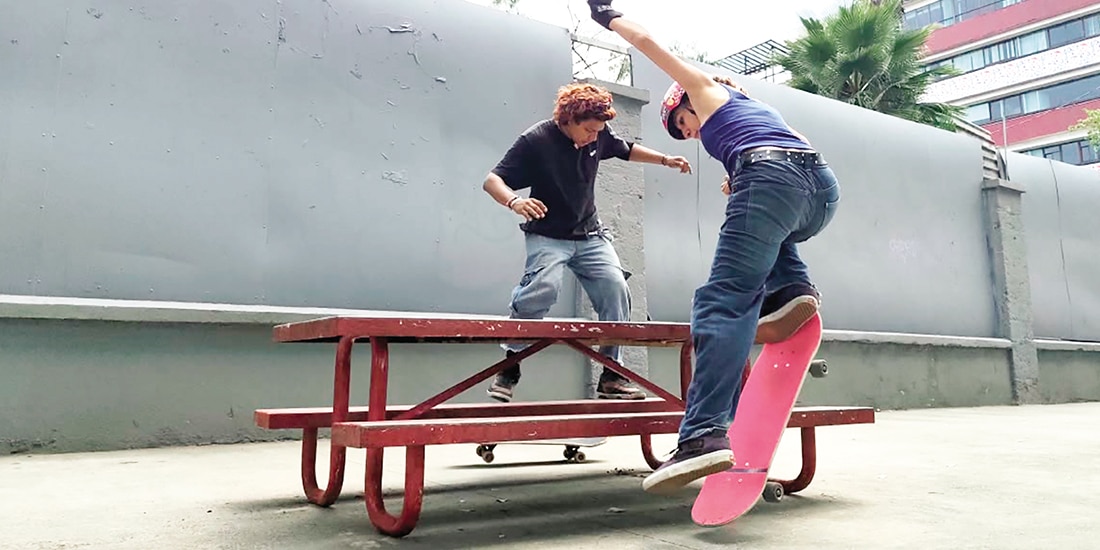 Dos jóvenes realizan trucos con su patineta en una banca, ayer.