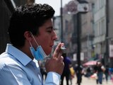 Un hombre fuma un cigarro sobre la calle de Madero.
