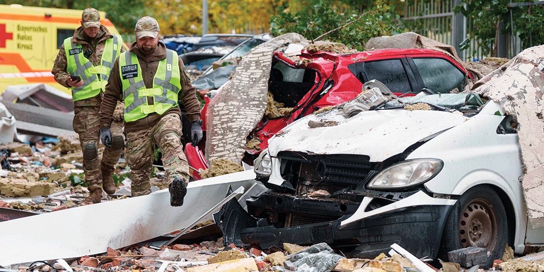 Policías caminan frente a autos destruidos por un ataque con drones rusos en Kiev, ayer.