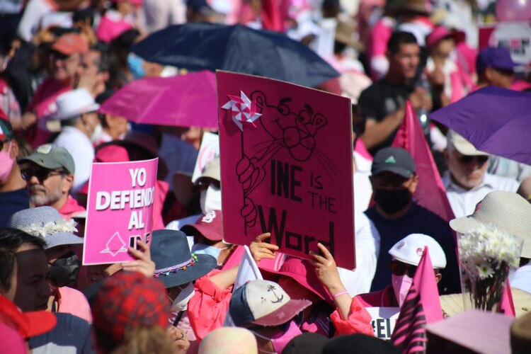 Manifestantes de la marcha en defensa del INE levantan sus carteles, pese a la aglomeración