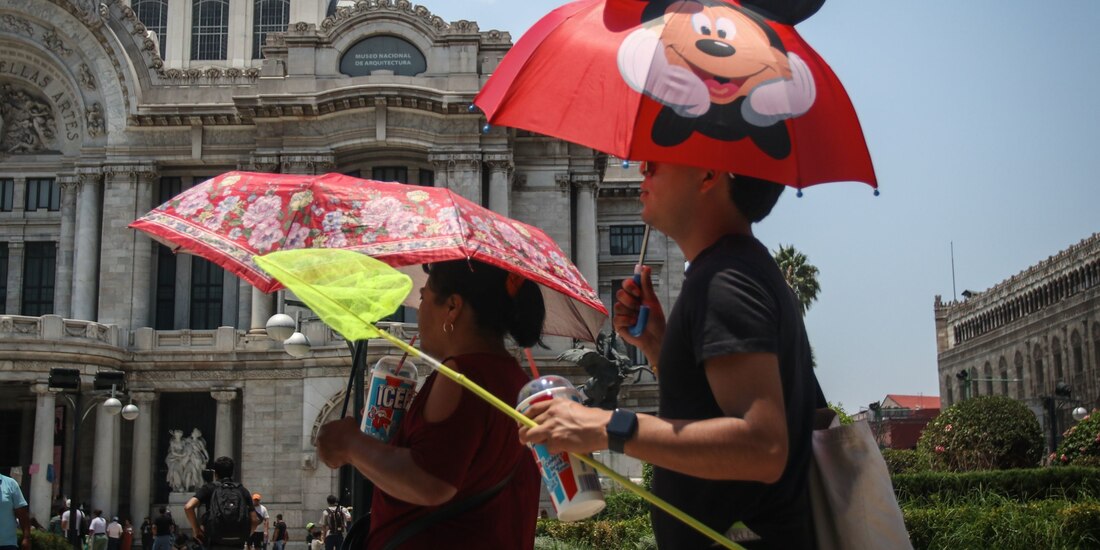 Personas se protegen del sol con sombrillas, ayer en la Ciudad de México.