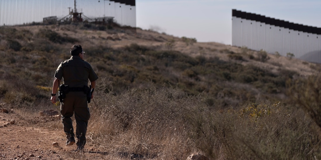 Un agente fronterizo camina hacia la valla que separa a Estados Unidos de México, durante un recorrido de vigilancia