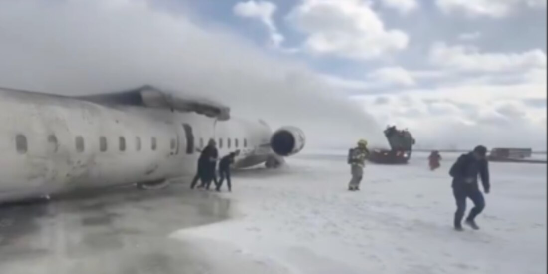 Bomberos ayudan a pasajeros afectados a descender de aeronave siniestrada en terminal de Canadá, ayer.