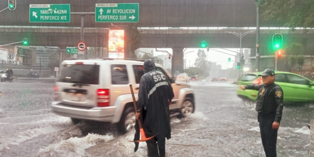 Policías destapan una coladera en medio de la lluvia, el 12 de julio.