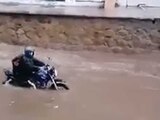 Un hombre se aferra a motocicleta, que es arrastrada por una inundación en Acapulco, donde este lunes impactó 'Max'