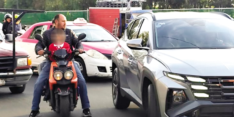 Un padre lleva a su hijo, sin casco, circulan entre carros, ayer, en Iztapalapa.