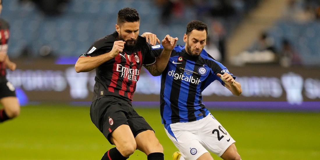 Olivier Giroud y Hakan Calhanoglu disputan el esférico durante el duelo de la Supercopa de Italia entre Milan e Inter de Milán.
