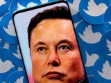 Elon Musk en un teléfono inteligente colocado en los logotipos impresos de Twitter.