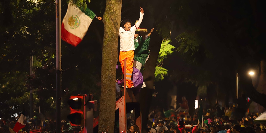 Jóvenes festejan el triunfo de México, el martes, sobre mobiliario público en Reforma.