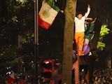 Jóvenes festejan el triunfo de México, el martes, sobre mobiliario público en Reforma.