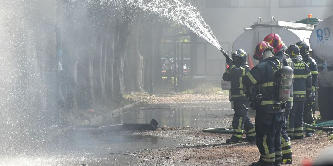 Bomberos apagan las llamas registradas en el estacionamiento de la alcaldía, ayer.