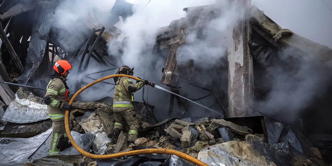 Bomberos apagan el fuego en un centro comercial atacado con misiles rusos, ayer.