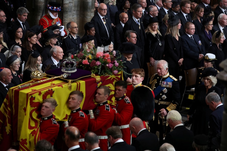 El ataúd de la monarca británica es cargado por guardias para su funeral, en Londres, mientras son seguidos por el rey Carlos III, ante invitados especiales, ayer.