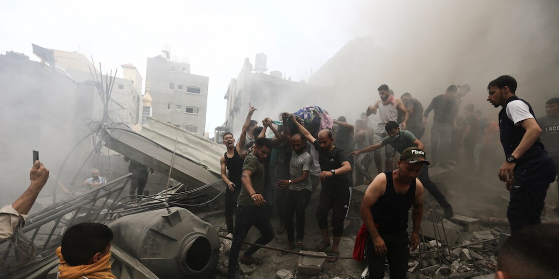 Palestinos recuperan el cadáver de una víctima tras la respuesta israelí, ayer.
