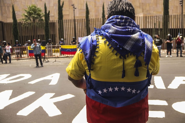 Una manifestante porta la bandera venezolana, frente a la Embajada de EU en México.