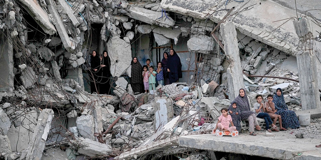 Mujeres y niños palestinos, entre escombros en la Ciudad de Gaza, ayer.