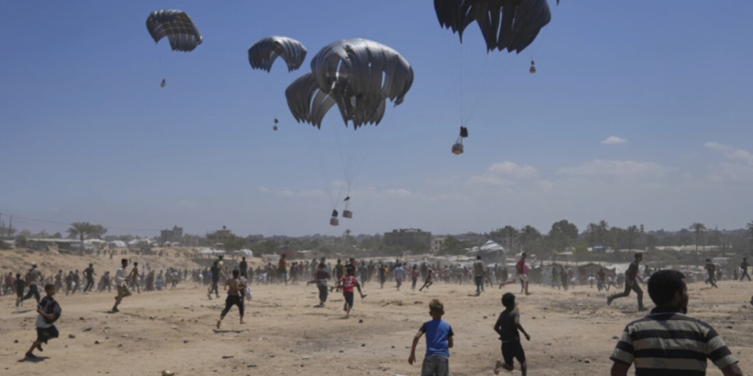 Palestinos se apresuran a recoger ayuda lanzada en paracaídas sobre Zawaida, ayer.