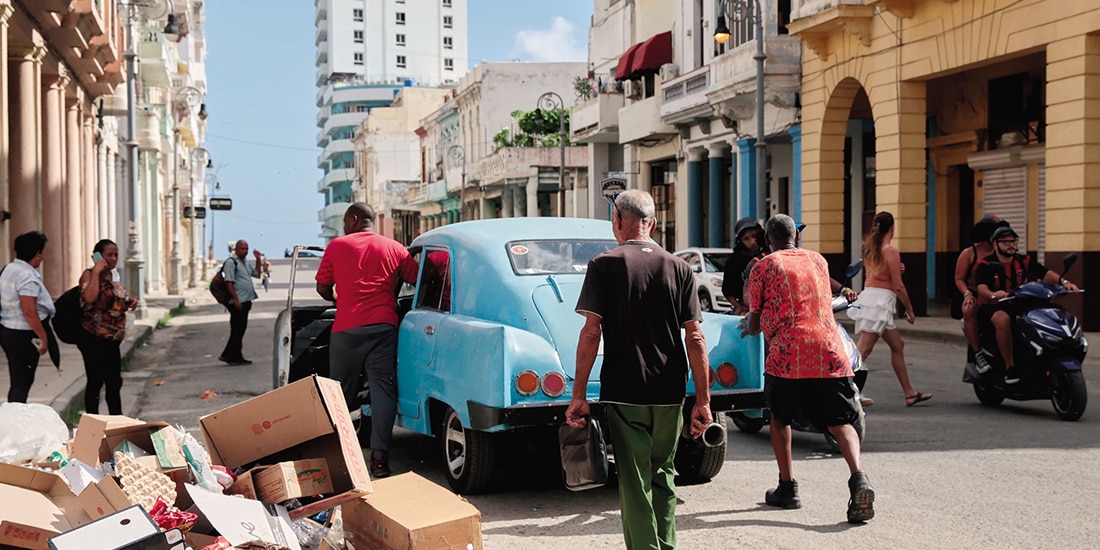 Hombres empujan un coche junto a un montón de basura en La Habana, ayer.